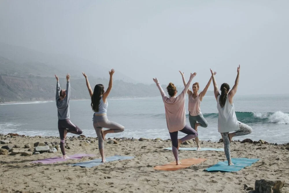 Women practising yoga on a beach