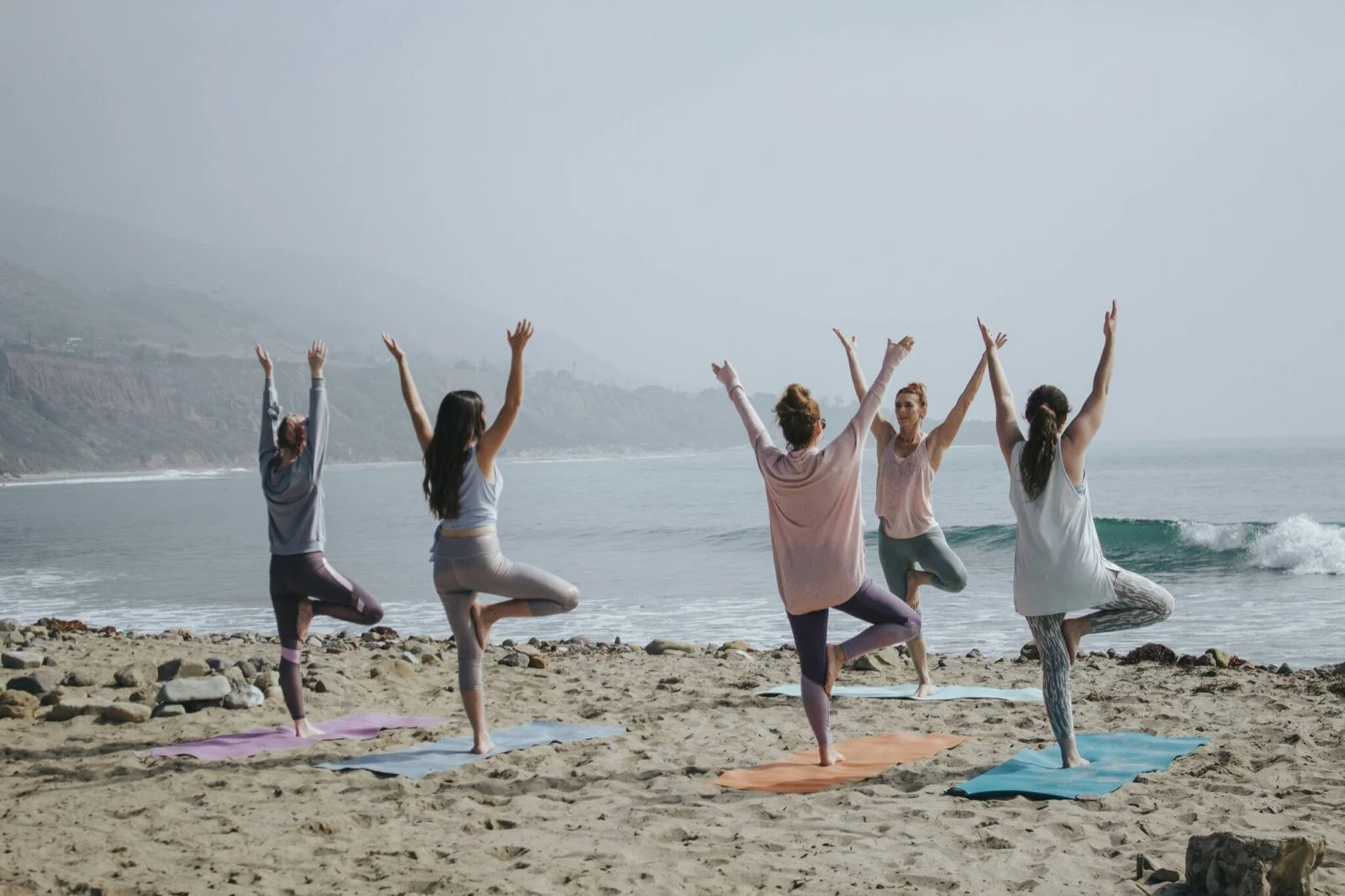 Women practising yoga on a beach