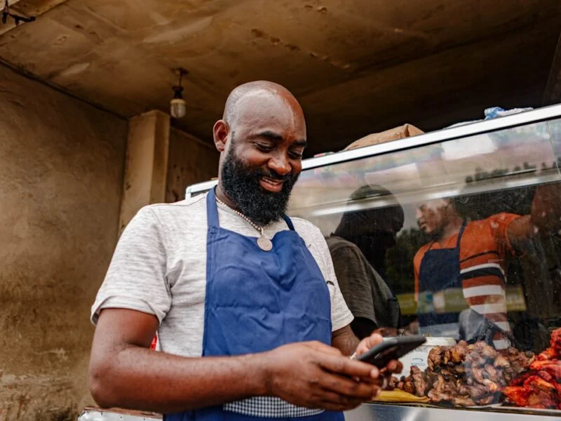 A local shop owner checking their business website on a smartphone behind the counter