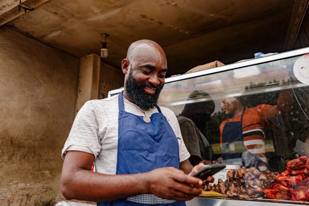 A local shop owner checking their business website on a smartphone behind the counter