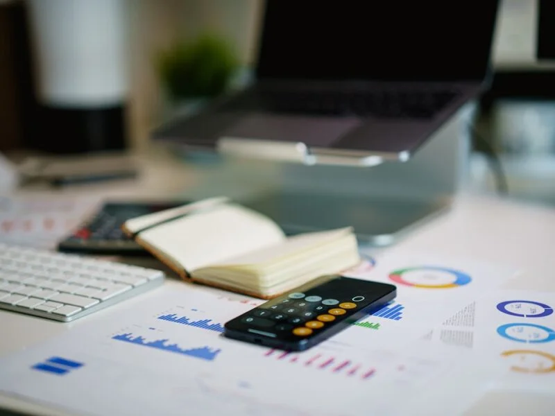 Accountant reviewing financial figures at a desk while a phone shows a local map search
