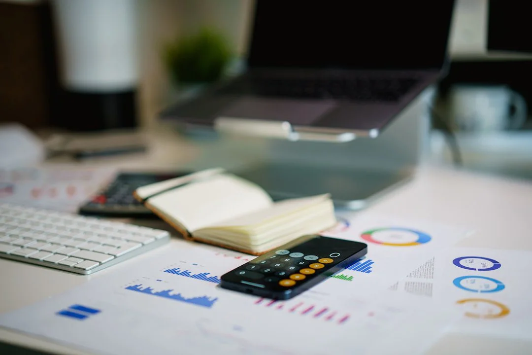 Accountant reviewing financial figures at a desk while a phone shows a local map search