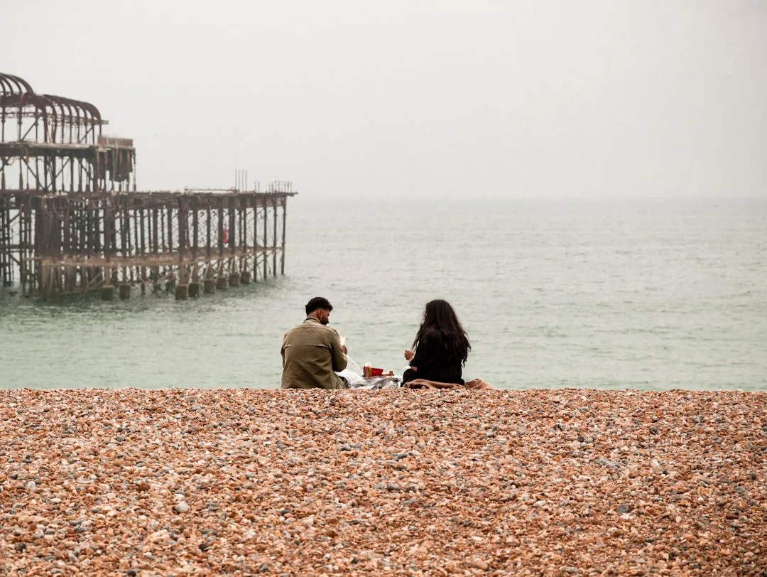 A person checking a mobile website on their phone while walking along Brighton seafront near the pier