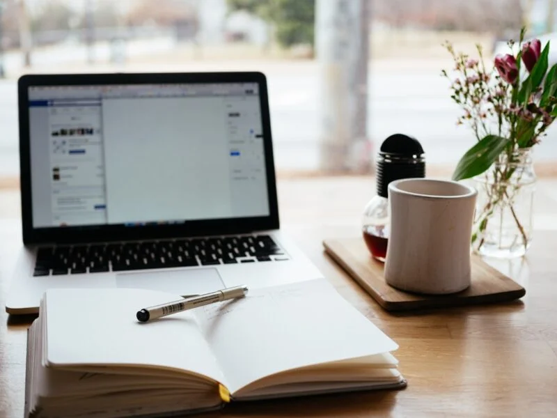 Overhead view of a writer planning a blog post structure on a laptop and notebook